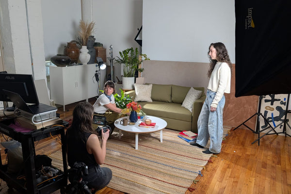 Photographer Emily Marie Schultz shooting tethered on the Sero Candles brand photoshoot while the art director adjusts a coffee table arrangement