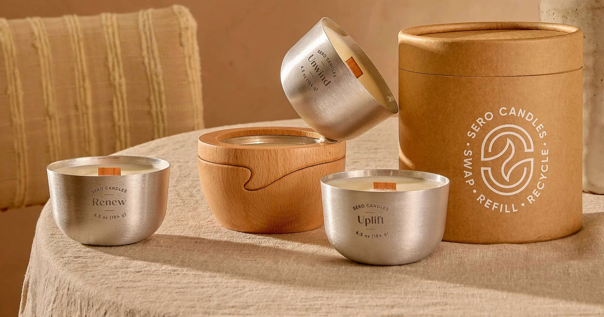 A Sero Starter Set on a linen table: two aluminum candle inserts, a beech wood holder, and the kraft tube printed Swap, Refill, Recycle.