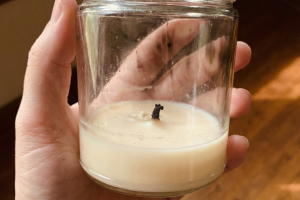 A burned-down glass candle jar with leftover wax residue