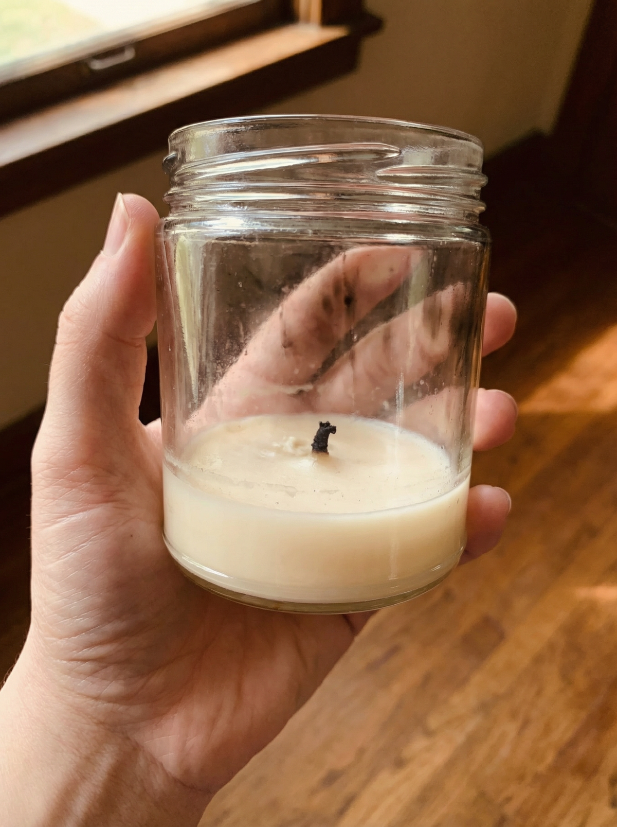 A burned-down glass candle jar with leftover wax residue
