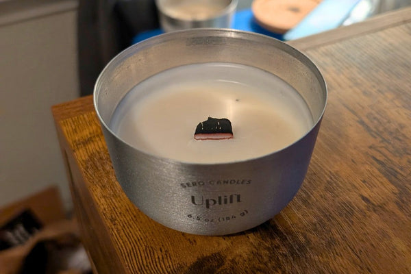 Charred wood wick in a Sero Candles aluminum container — trim before relighting
