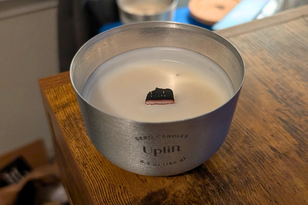 Charred wood wick in a Sero Candles aluminum container — trim before relighting